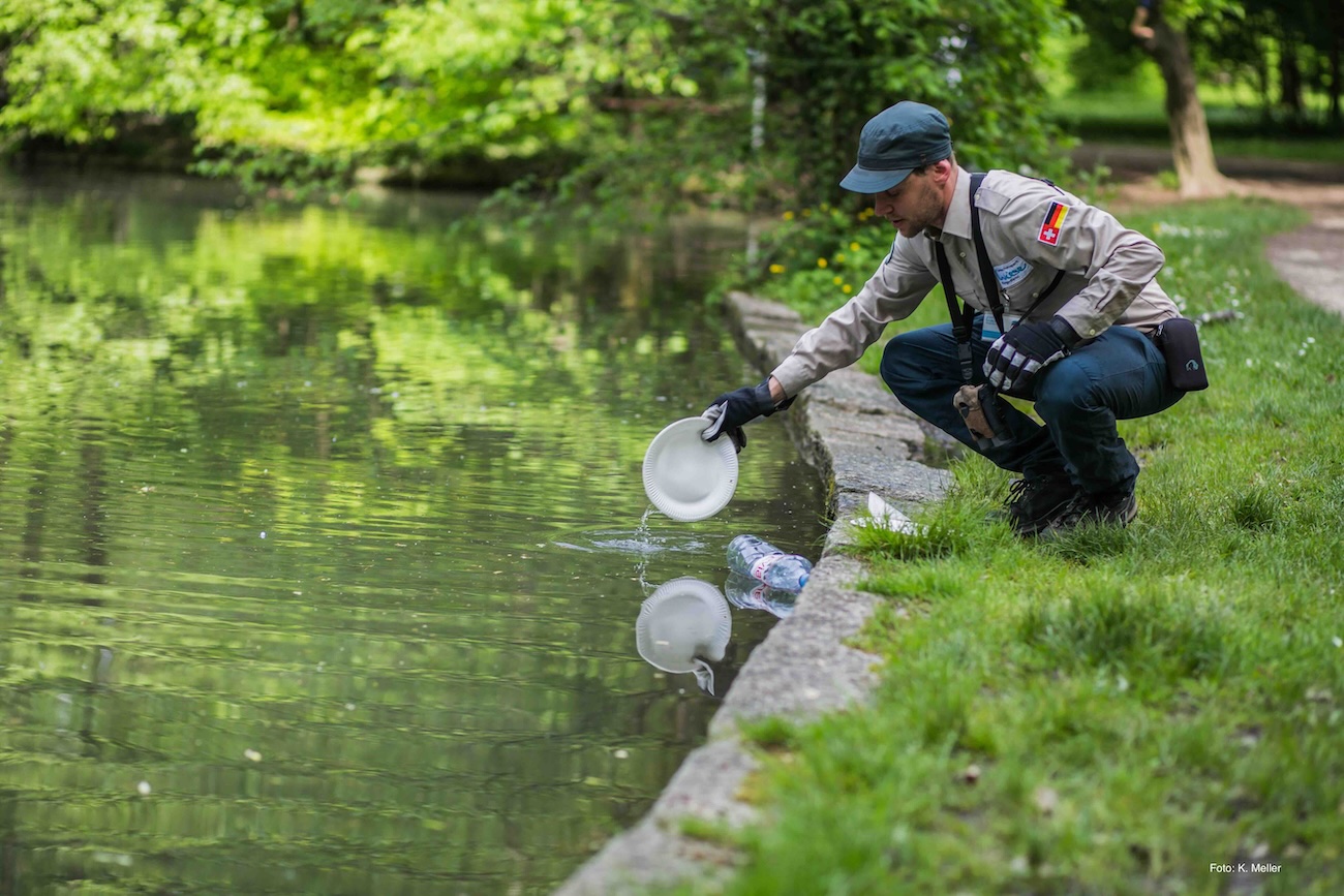 Ranger fischt Abfälle aus einem Waldweiher.